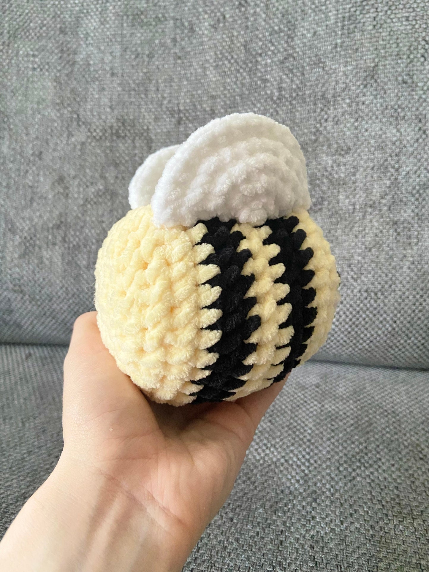 The back of a finished crochet bee behind a neutral background