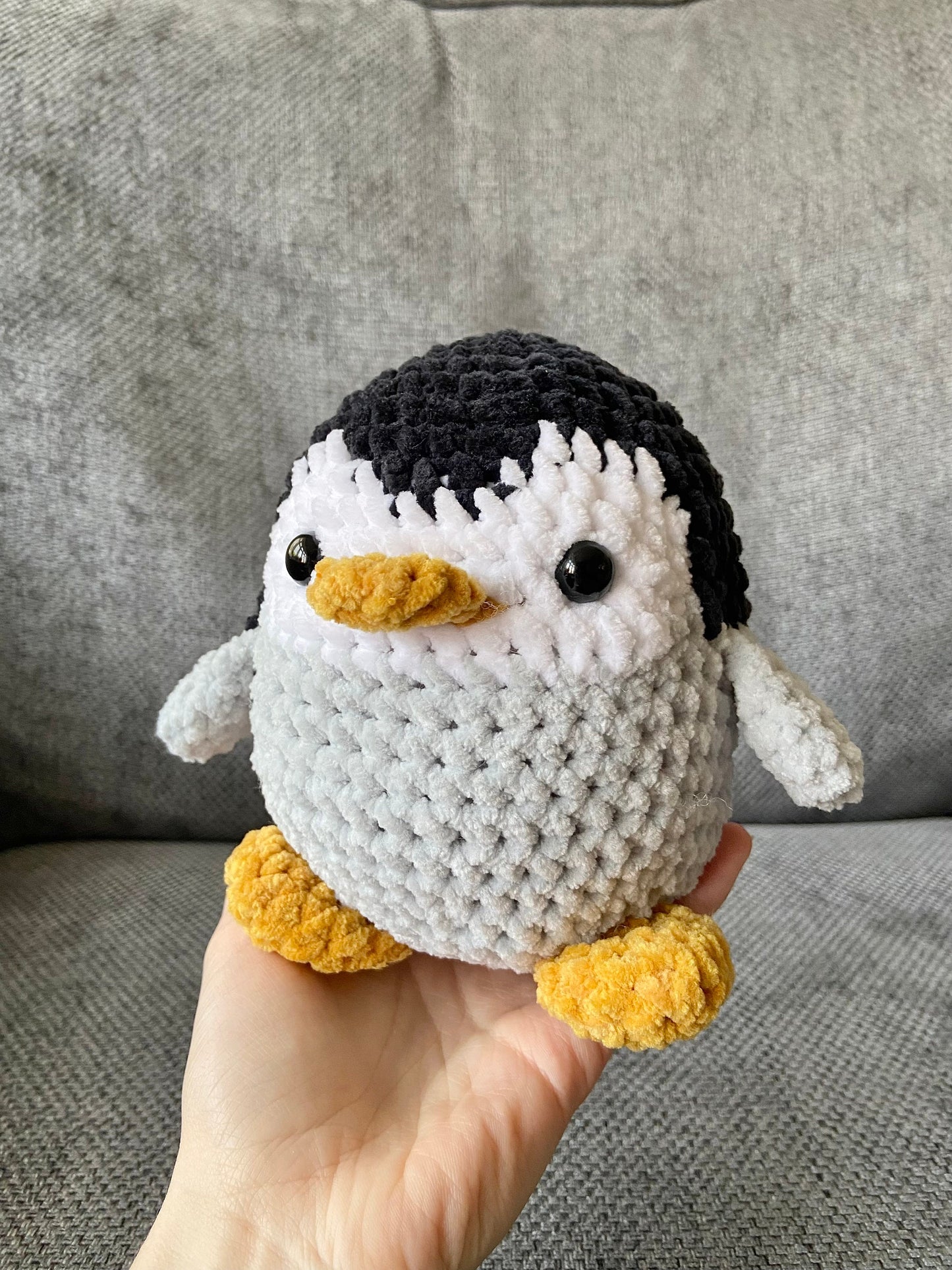 Handmade crochet penguin plush with black and grey body, white belly, and orange beak