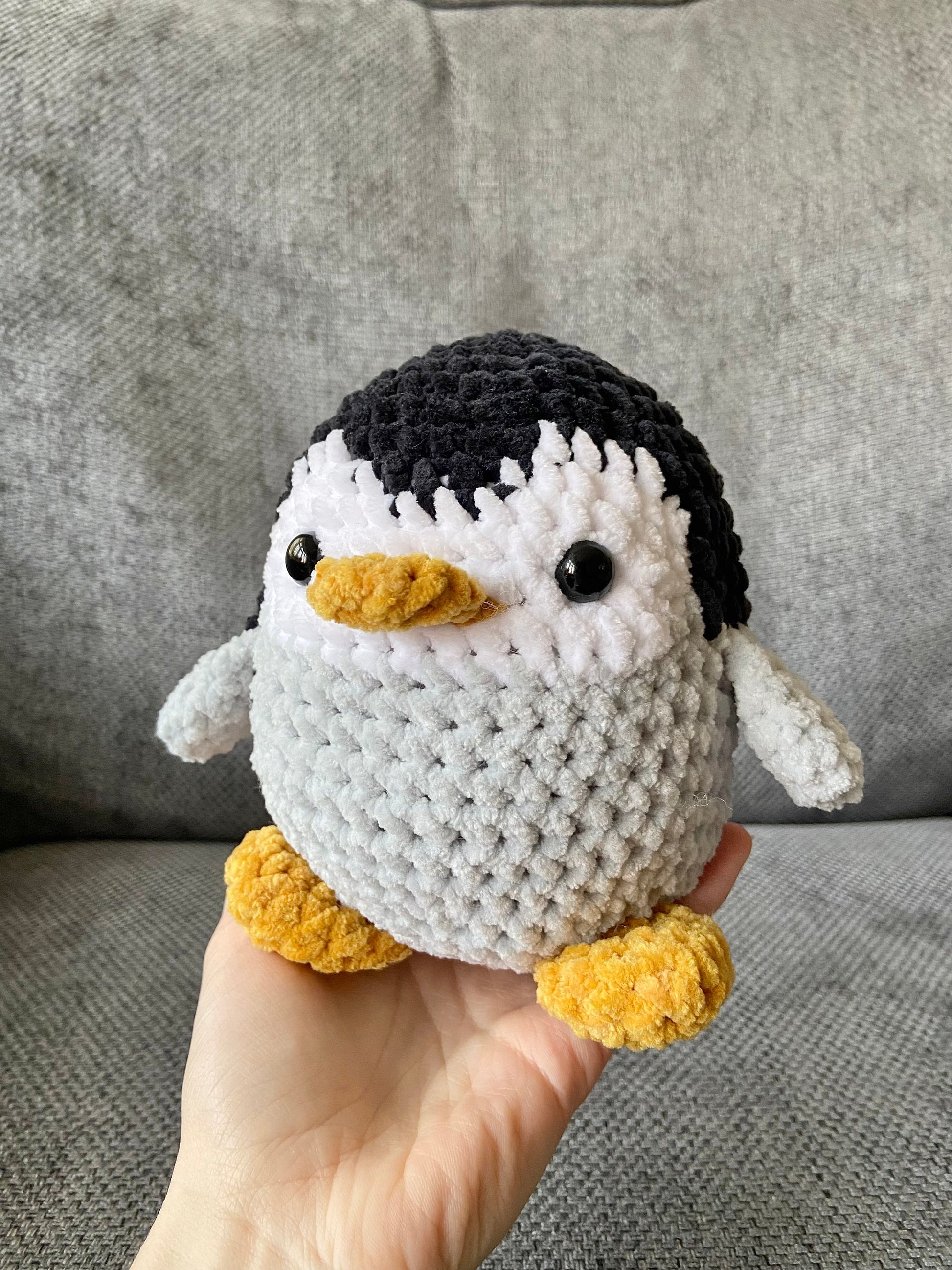 Handmade crochet penguin plush with black and grey body, white belly, and orange beak